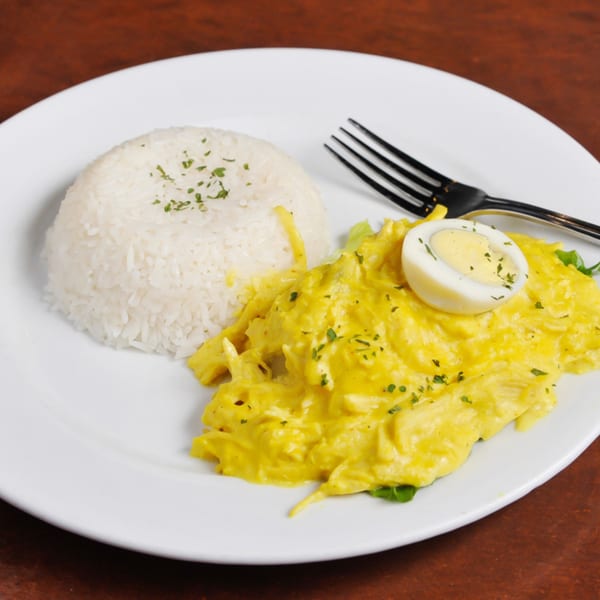 Peruvian Aji de Gallina, a creamy yellow chicken dish, with white rice and a hard-boiled egg.