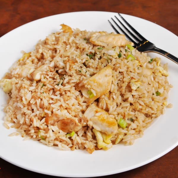 Sabor Inka's Peruvian arroz chaufa with chicken, rice, scrambled egg, and green onions on a white plate.