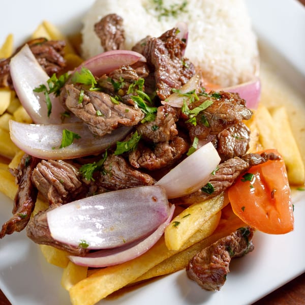 Peruvian Lomo Saltado with beef, red onions, tomatoes, french fries, and white rice.